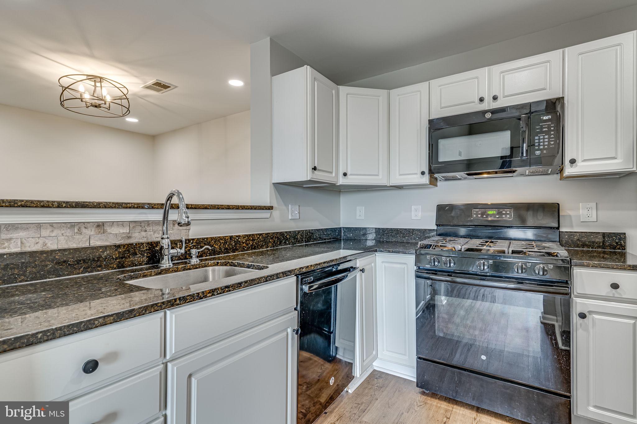 1067 Gardenview Loop, Unit 304 Woodbridge, VA 22191 - Photo 9 of 36 a kitchen with granite countertop a sink a stove and cabinets