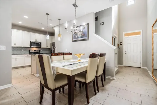 a dining room with stainless steel appliances kitchen island granite countertop a dining table chairs and a refrigerator