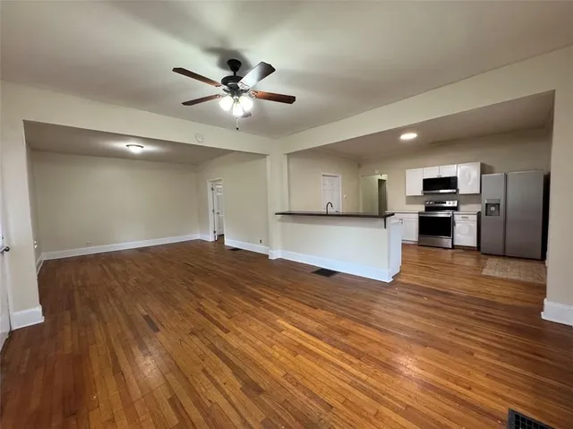 a view of empty room with wooden floor and window