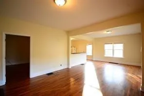 a view of an empty room and wooden floor and a window