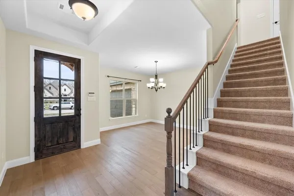 an empty room with wooden floor chandelier and windows