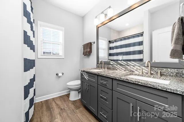 a bathroom with a granite countertop sink toilet and mirror