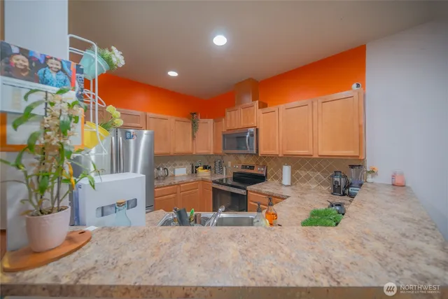 a kitchen with stainless steel appliances kitchen island granite countertop a living room dining room and utility room