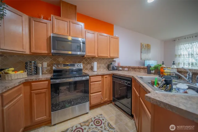 a kitchen with stainless steel appliances granite countertop a stove a sink dishwasher and a microwave oven with cabinets