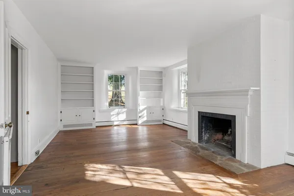 a view of empty room with wooden floor and fireplace