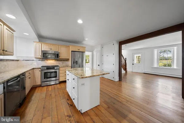 a large kitchen with stainless steel appliances granite countertop a stove a sink dishwasher and a microwave oven with wooden floor