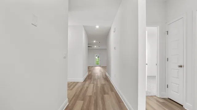 a view of a hallway with wooden floor and a bathroom