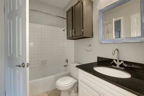 a bathroom with a granite countertop sink toilet and mirror