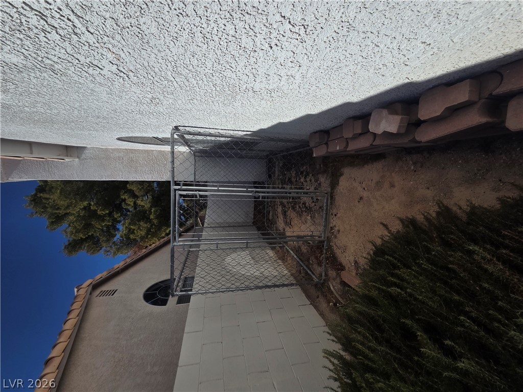 1429 Hawkwood Road Henderson, NV 89014 - Photo 50 of 53 A functional side yard features concrete block walls, stucco finishes, and a chain-link kennel enclosure.