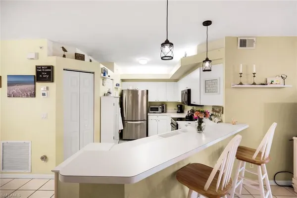 a kitchen with stainless steel appliances a refrigerator a sink a stove a dining table and chairs