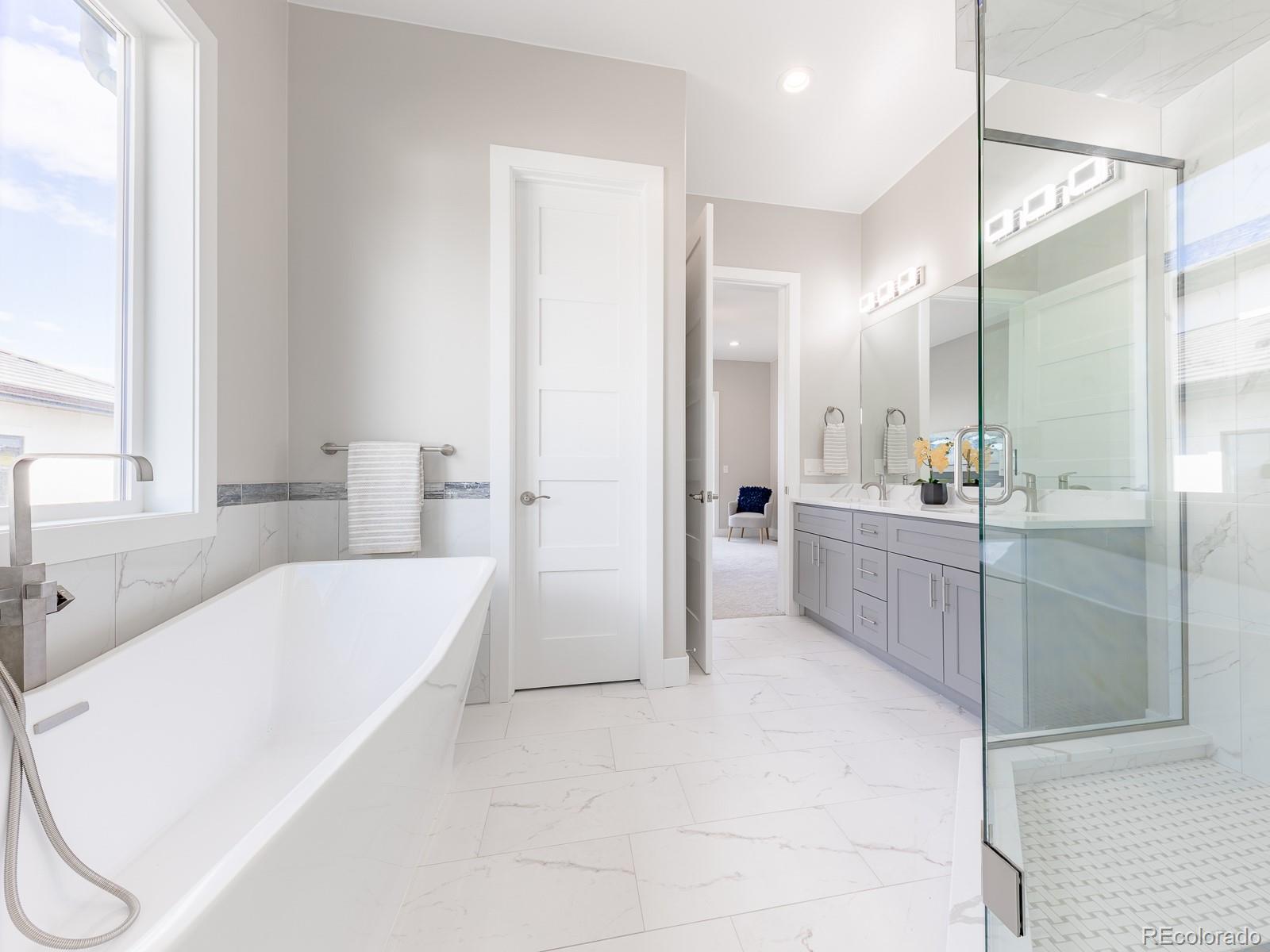 9540 Orion Way Arvada, CO 80007 - Photo 18 of 40 a bathroom with a tub a sink a mirror and a shower