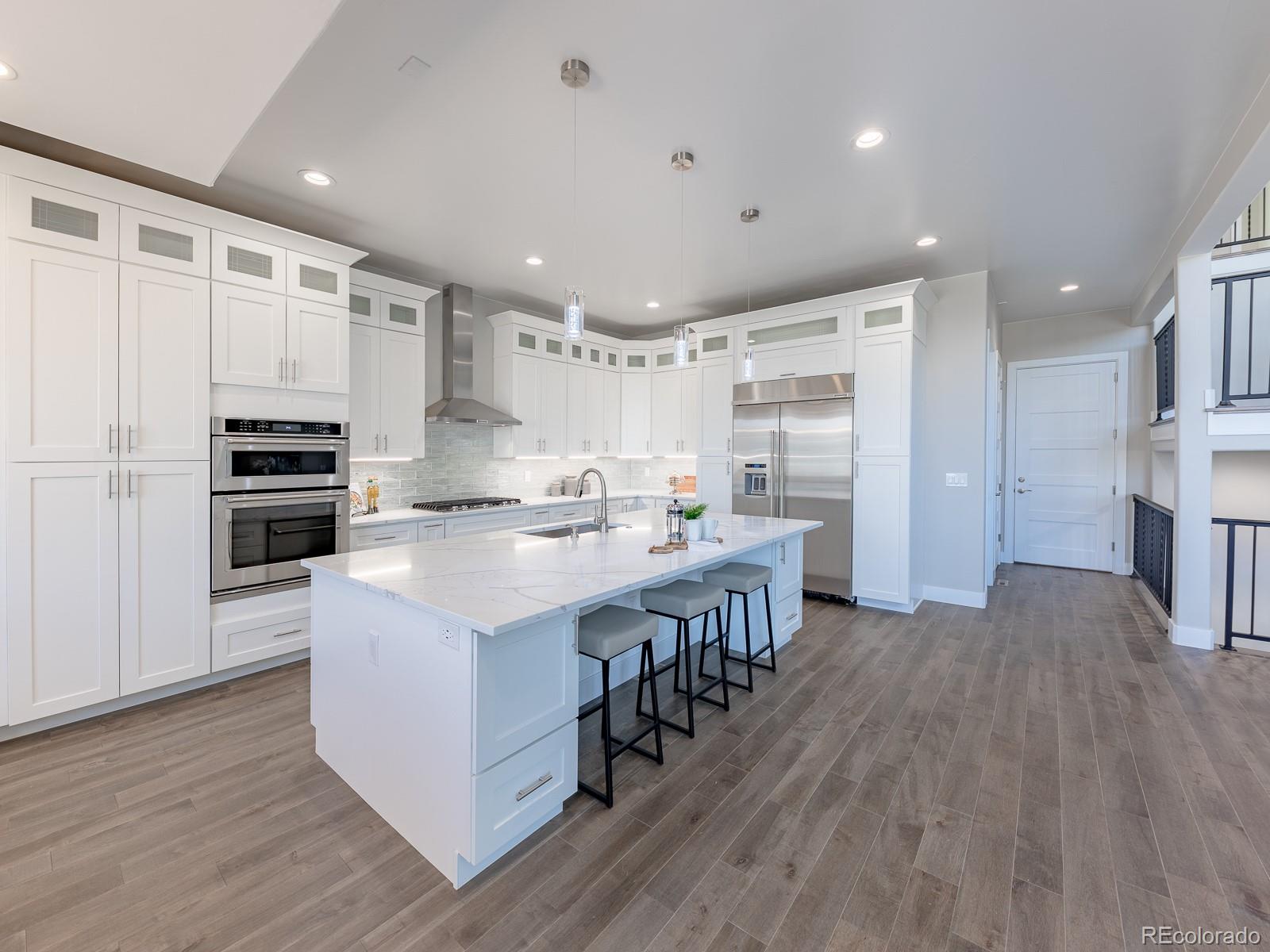 9540 Orion Way Arvada, CO 80007 - Photo 3 of 40 a kitchen with stainless steel appliances kitchen island granite countertop a refrigerator a stove a sink and a oven with wooden floor
