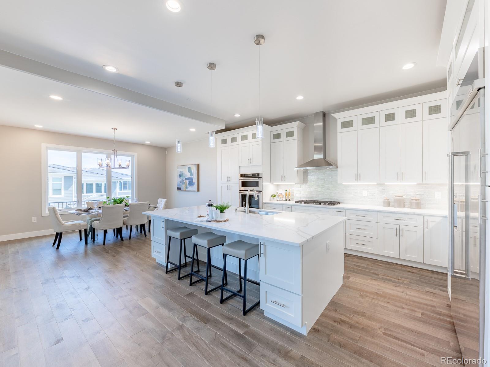 9540 Orion Way Arvada, CO 80007 - Photo 8 of 40 a large white kitchen with lots of counter top space and dining table