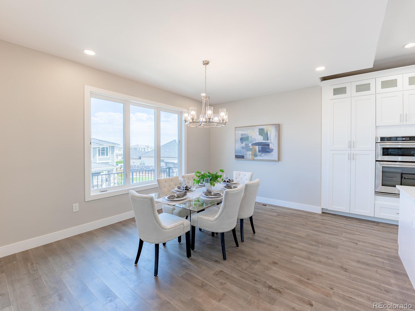 9540 Orion Way Arvada, CO 80007 - Photo 9 of 40 a dining room with furniture a chandelier and wooden floor