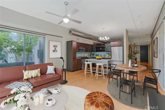 a living room with furniture kitchen view and a large window