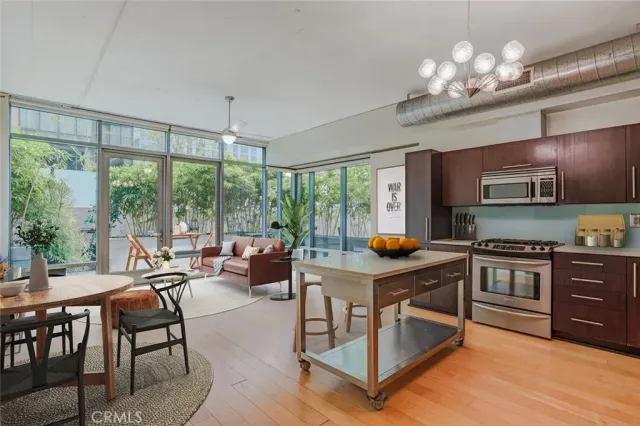 a kitchen with stainless steel appliances granite countertop a stove top oven a sink dishwasher a dining table and chairs with wooden floor