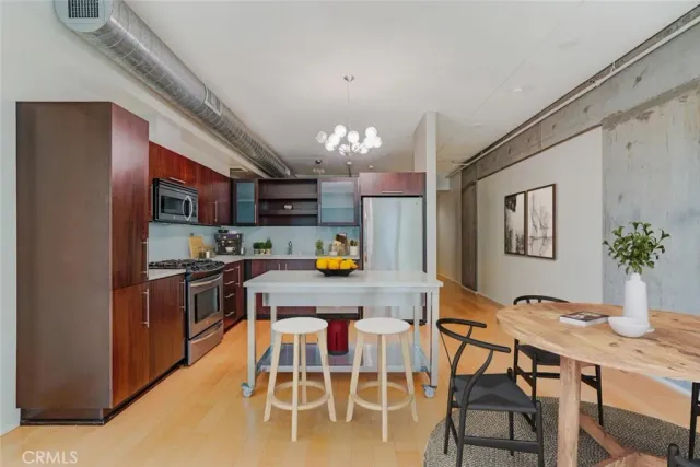 a kitchen with stainless steel appliances kitchen island granite countertop a dining table chairs and refrigerator