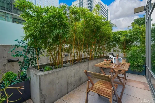 a backyard of a house with table and chairs potted plants and large tree