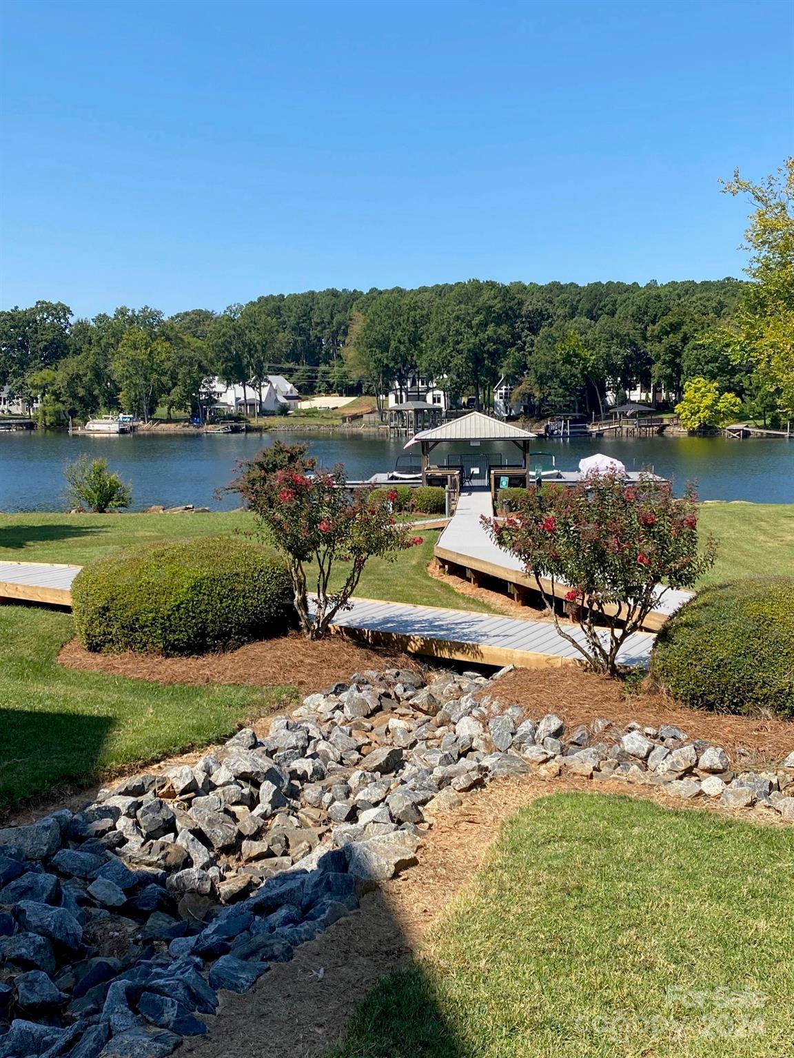 18225 Taffrail Way Cornelius, NC 28031 - Photo 26 of 30 a view of a lake with lawn chairs and large trees