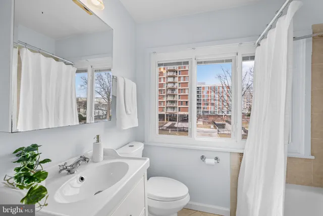 a bathroom with a sink a mirror a window and a toilet