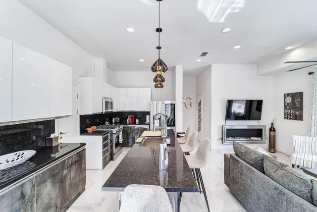 a living room with furniture kitchen area and a chandelier