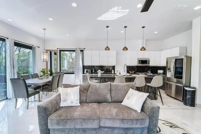 a living room with furniture kitchen area and a large window
