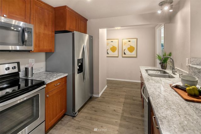 a kitchen with stainless steel appliances granite countertop a refrigerator a stove top oven a sink and dishwasher