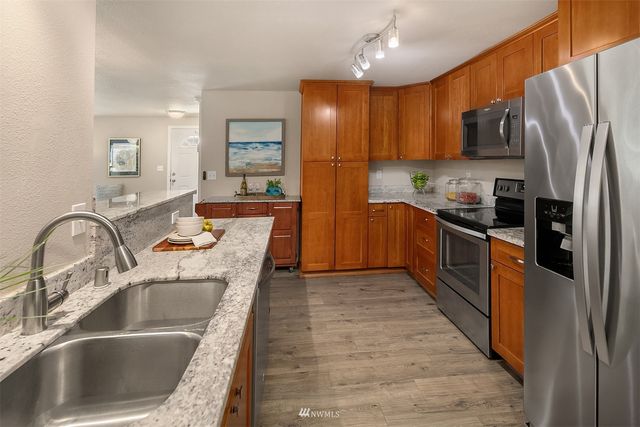 a kitchen with stainless steel appliances granite countertop a sink refrigerator and cabinets