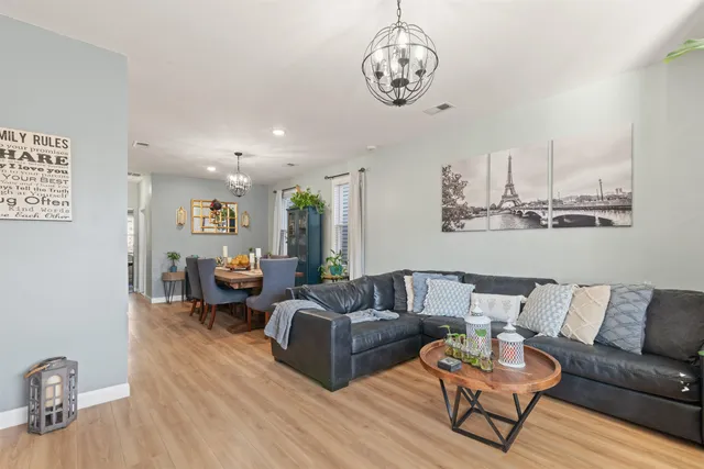 a living room with furniture kitchen view and a wooden floor