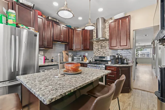 a kitchen with granite countertop a table chairs stove refrigerator and cabinets