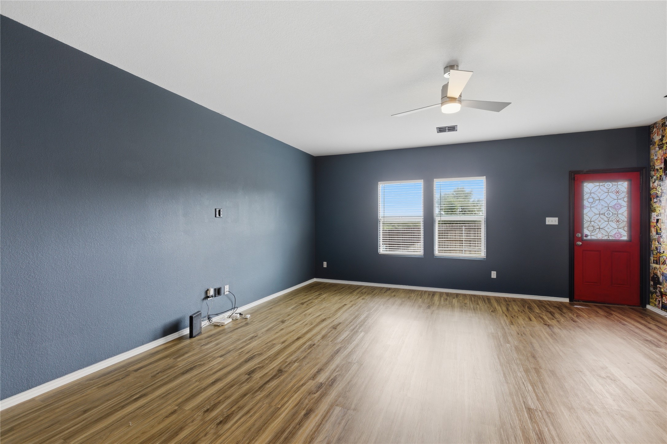 116 Night Riders Way Jarrell, TX 76537 - Photo 10 of 40 Spacious living area featuring wood-finish flooring, a contemporary ceiling fan with integrated lighting, and a prominent accent wall