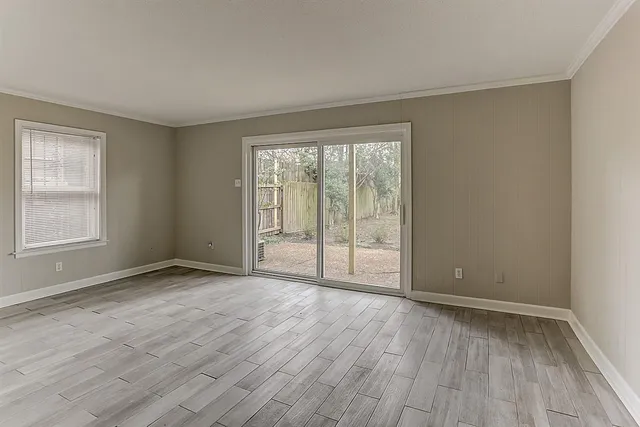 a view of an empty room with wooden floor and a window