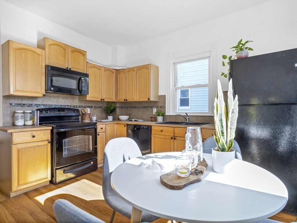 8 Marbury Terrace, Unit 1 Boston, MA 02130 - Photo 7 of 35 a kitchen with stainless steel appliances granite countertop a stove a kitchen island a dining table and chairs