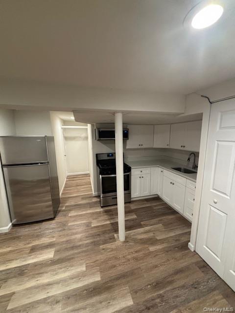 28 West Neck Road, Unit 14 Huntington, NY 11743 - Photo 11 of 13 Kitchen with appliances with stainless steel finishes, white cabinetry, dark wood-style floors, and exhaust hood