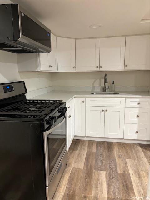 28 West Neck Road, Unit 14 Huntington, NY 11743 - Photo 5 of 13 Kitchen with stainless steel appliances, white cabinets, and light wood-style floors