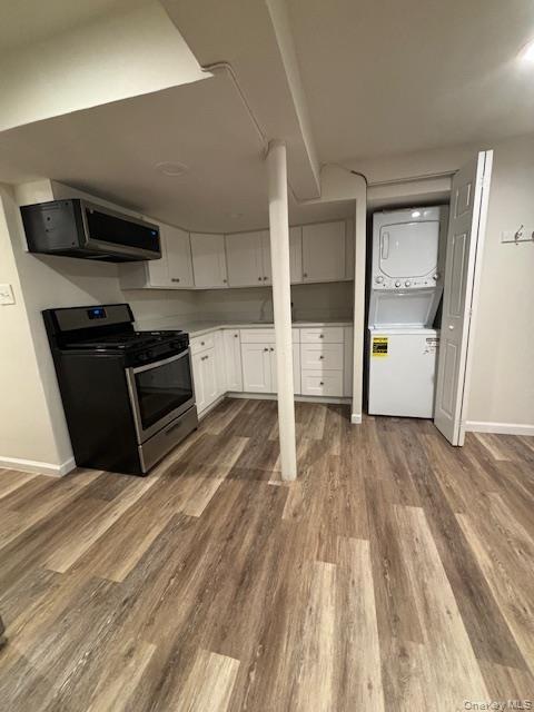 28 West Neck Road, Unit 14 Huntington, NY 11743 - Photo 6 of 13 Kitchen with gas range, stacked washer and clothes dryer, white cabinetry, light countertops, and light wood-style flooring