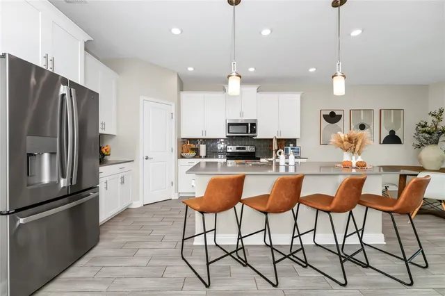 a kitchen with stainless steel appliances granite countertop a stove top oven a sink dishwasher a dining table and chairs with wooden floor