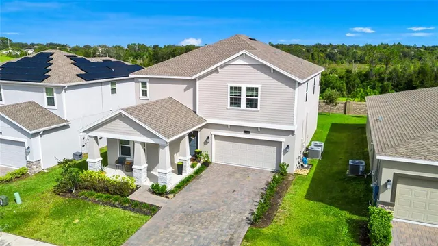 a view of a white house next to a yard with big trees