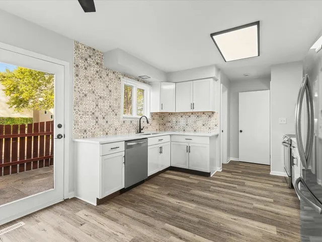 a kitchen with a white cabinets and wooden floor