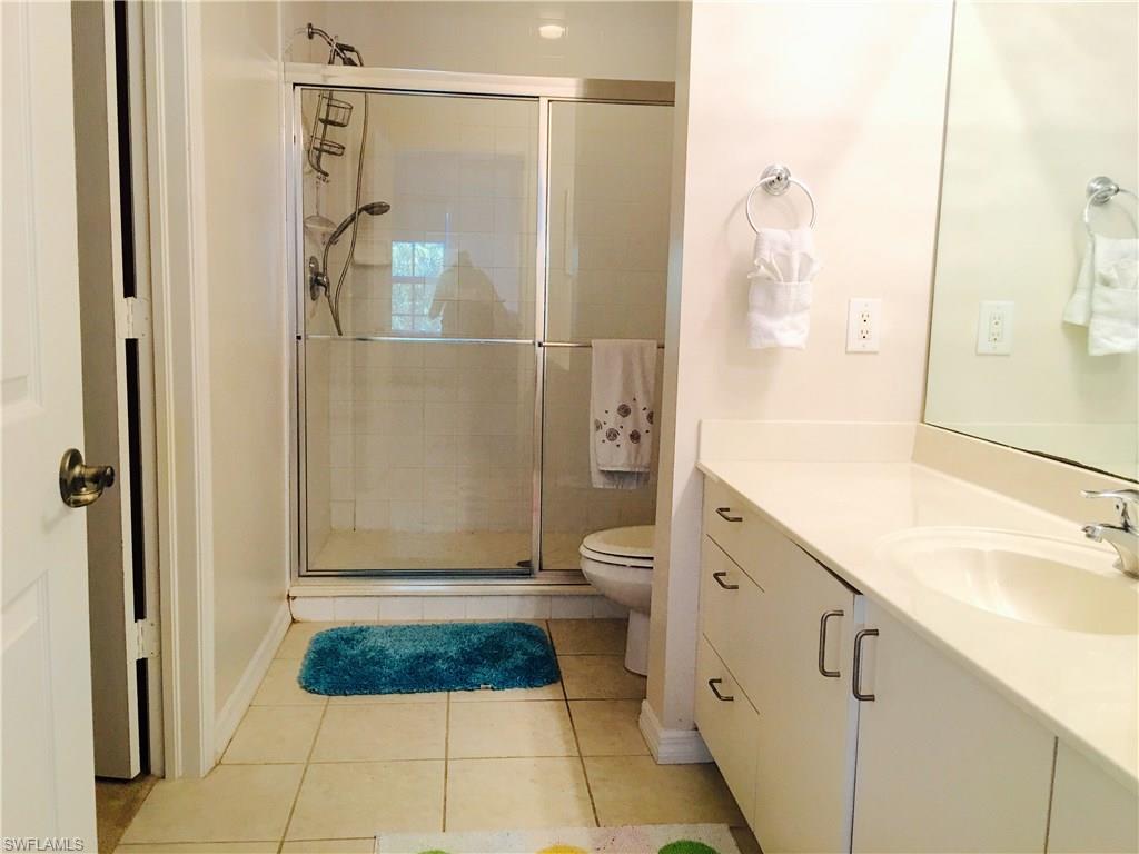 4530 Botanical Pl Circle, Unit 206 Naples, FL 34112 - Photo 11 of 25 a bathroom with a granite countertop shower mirror and a toilet