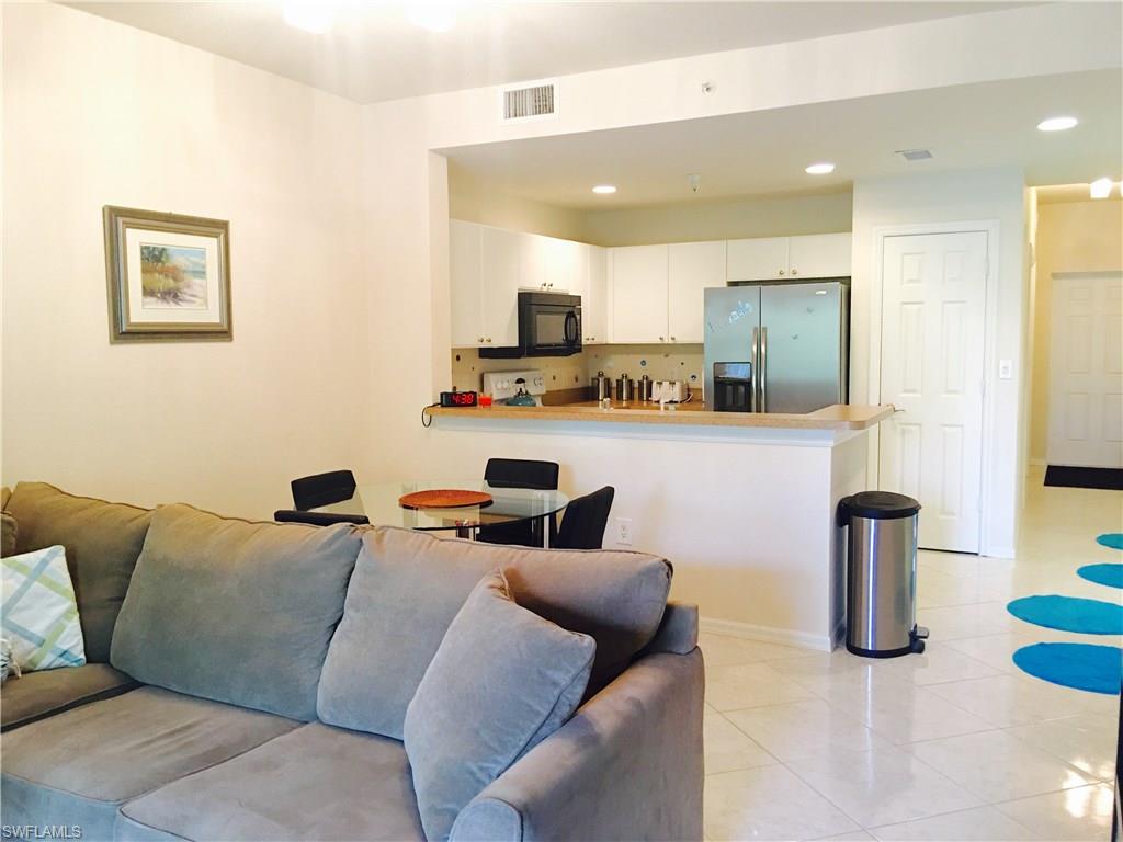 4530 Botanical Pl Circle, Unit 206 Naples, FL 34112 - Photo 13 of 25 a living room with furniture kitchen view and a flat screen tv