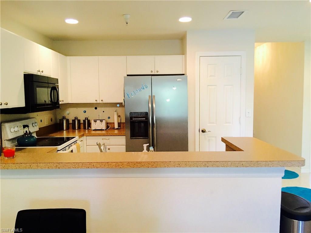 4530 Botanical Pl Circle, Unit 206 Naples, FL 34112 - Photo 14 of 25 a kitchen with kitchen island a counter top space cabinets and stainless steel appliances