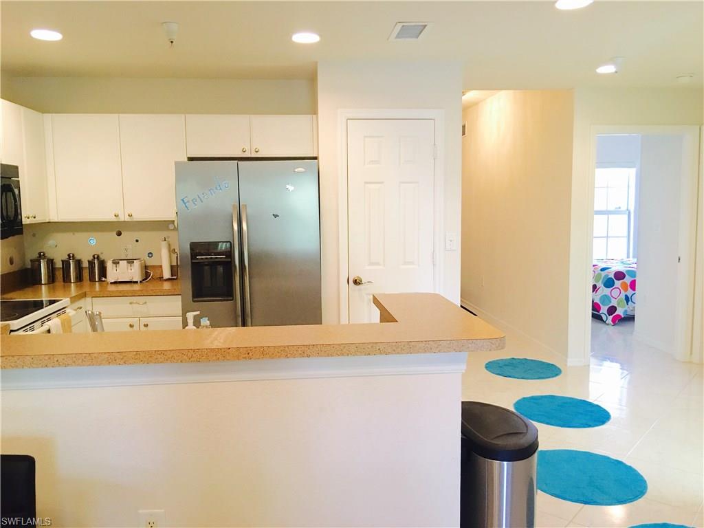 4530 Botanical Pl Circle, Unit 206 Naples, FL 34112 - Photo 15 of 25 a kitchen with stainless steel appliances kitchen island granite countertop a sink and a refrigerator