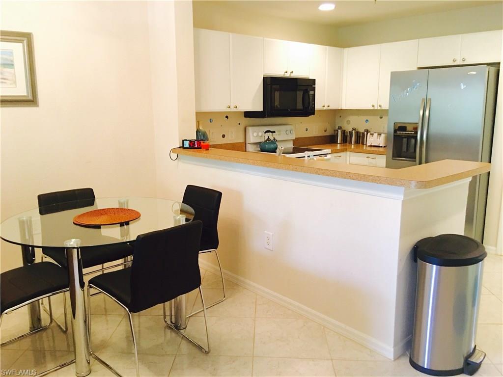 4530 Botanical Pl Circle, Unit 206 Naples, FL 34112 - Photo 16 of 25 a kitchen with a table chairs refrigerator and microwave