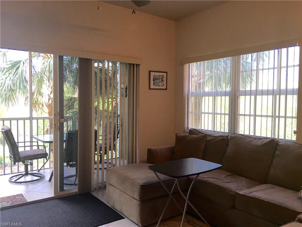 4530 Botanical Pl Circle, Unit 206 Naples, FL 34112 - Photo 18 of 25 a living room with furniture and a floor to ceiling window