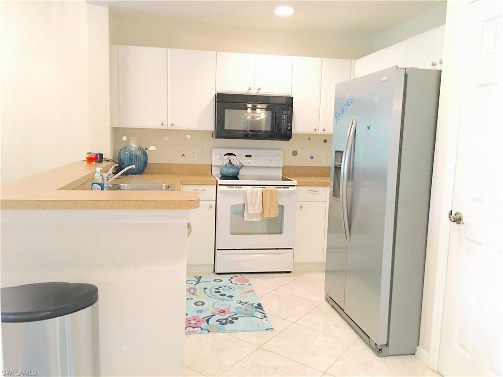 4530 Botanical Pl Circle, Unit 206 Naples, FL 34112 - Photo 4 of 25 a kitchen with stainless steel appliances granite countertop a refrigerator and a sink