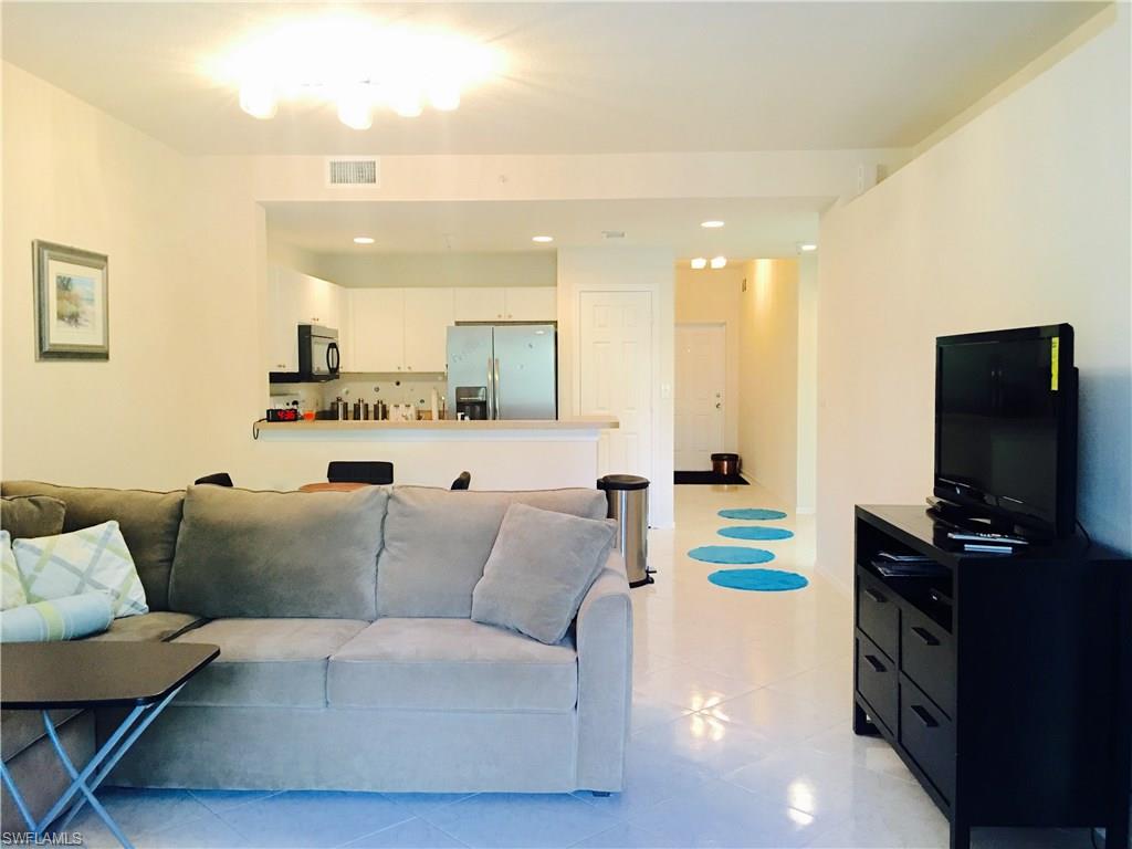4530 Botanical Pl Circle, Unit 206 Naples, FL 34112 - Photo 9 of 25 a living room with furniture and a flat screen tv