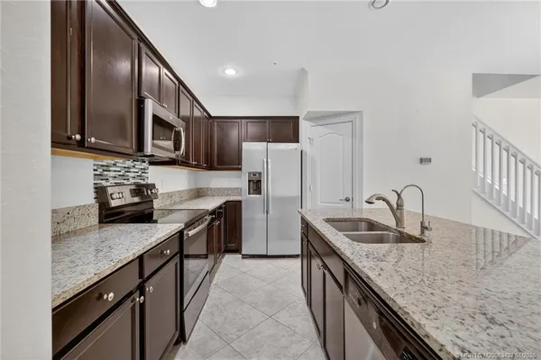 a kitchen with stainless steel appliances granite countertop a sink stove microwave and refrigerator