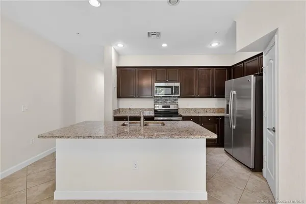 a kitchen with stainless steel appliances granite countertop a refrigerator a stove a sink a microwave and island