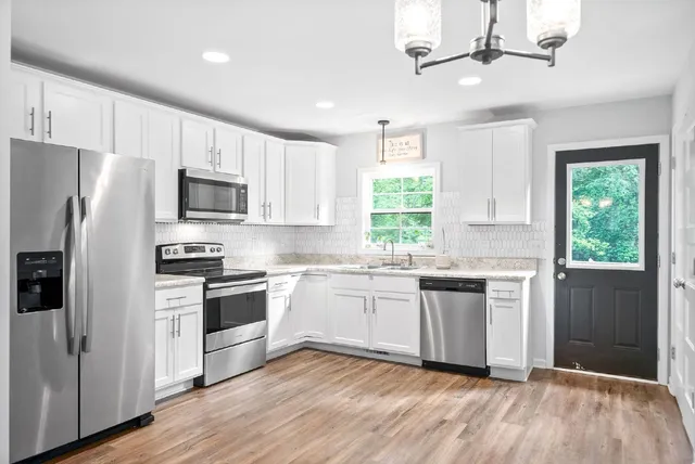 a kitchen with granite countertop stainless steel appliances a sink cabinets a window and a counter space